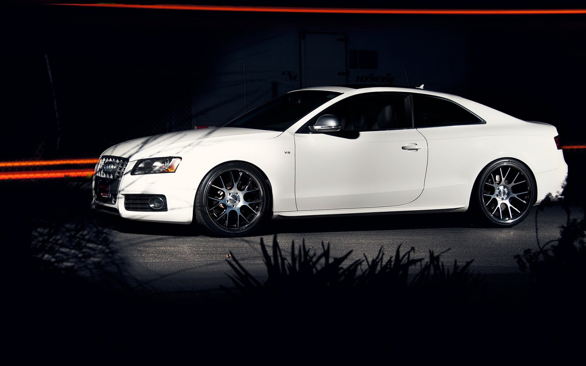 Белый Audi A5 под светом фонаря в темном переулке